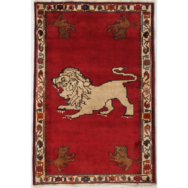 Vintage Persian Gabbeh hand-knotted wool rug with a red field and a large central lion motif, with smaller stylized lions...