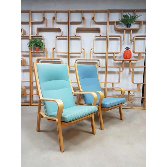 - High back armchairs designed by Hans J. Wegner in the 1950s - Open wooden frame - Wool fabric in green/blue color This...