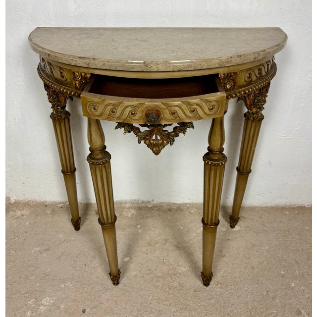 Elegant Italian demi-lune console table crafted in carved polychromed wood and topped with a shaped marble surface. Raised...