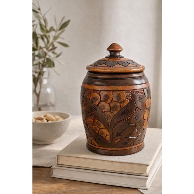 Hand-carved wooden canister with sculptural floral relief and a rich two-tone finish, offering both functional storage and...