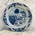 A beautiful antique Dutch Delft blue and white plate, hand-painted with a picturesque riverside landscape featuring a...