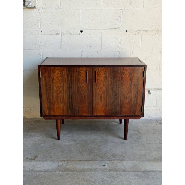 This elegant low-profile sideboard credenza features a streamlined rectangular silhouette elevated by four round tapered...