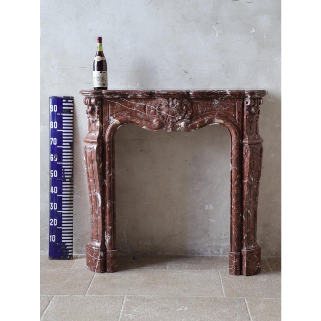 This beautiful antique fireplace is a hand-carved Trois Coquilles model, crafted from stunning Rouge Royal marble. This...