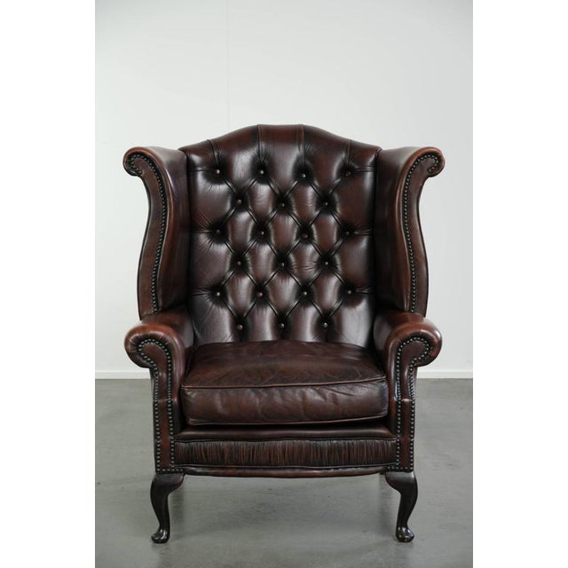 This elegant Chesterfield wing armchair is made of cowhide leather and offers a comfortable seat. The armchair features a...