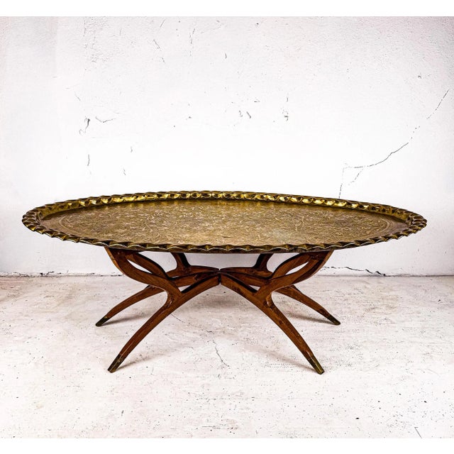 A mid-century modern brass tray table featuring a scalloped solid brass tray top with intricate hand-etched detailing and...