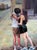 A luminous and emotive oil painting capturing the beauty of an intimate embrace in an urban setting. The soft brushstrokes...