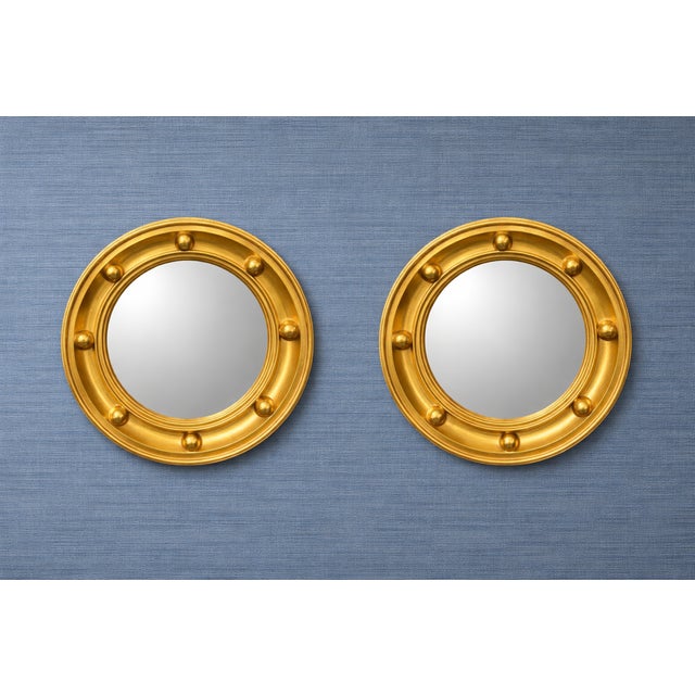 Elegant pair of round giltwood convex wall mirrors featuring a classic studded surround and rich, warm gold finish. The...