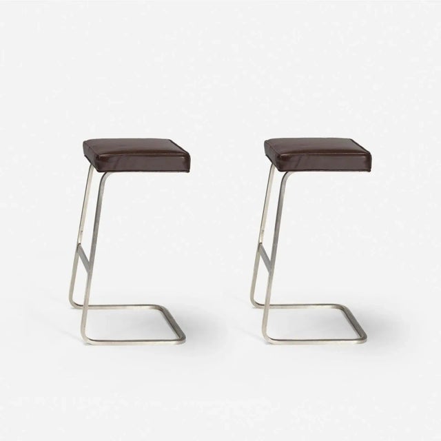 Modern pair of bar stools. The stools are done in brown leather. The finish is muted gold ‘bronze. The stools are made of...