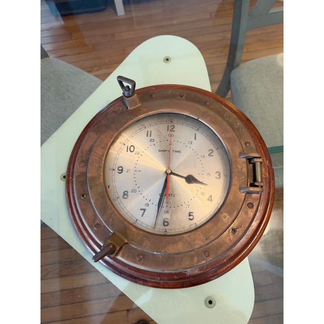 Vintage nautical porthole ship clock. Has brass port hole trim and carved wood. Diameter: 14”