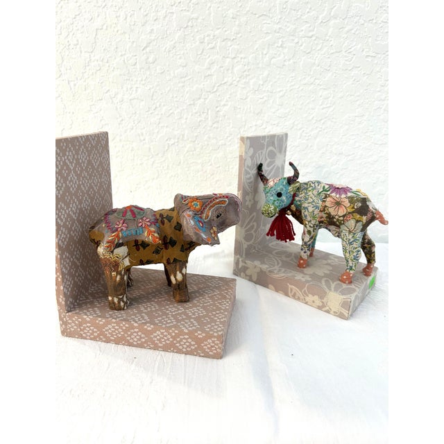 Charming pair of bookends from India featuring cloth covered wood platforms, one with a hard resin figural elephant and...