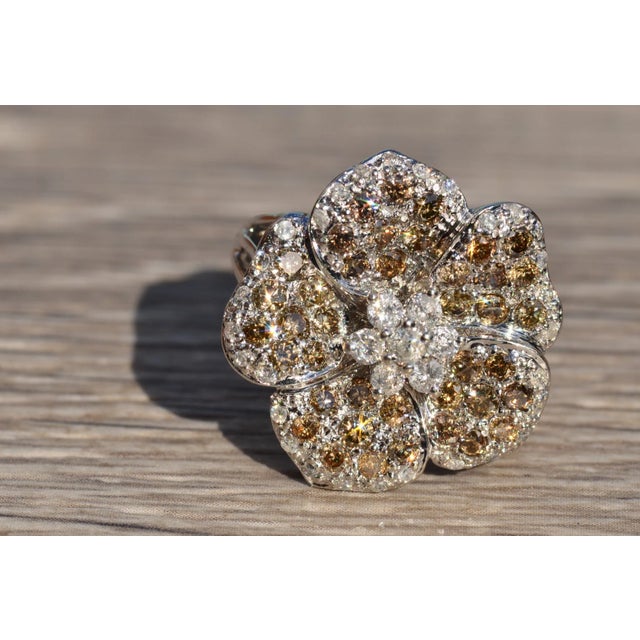 The Dallas Impressive Flower Ring set in the center with a white diamond cluster raised about a background of pave set...