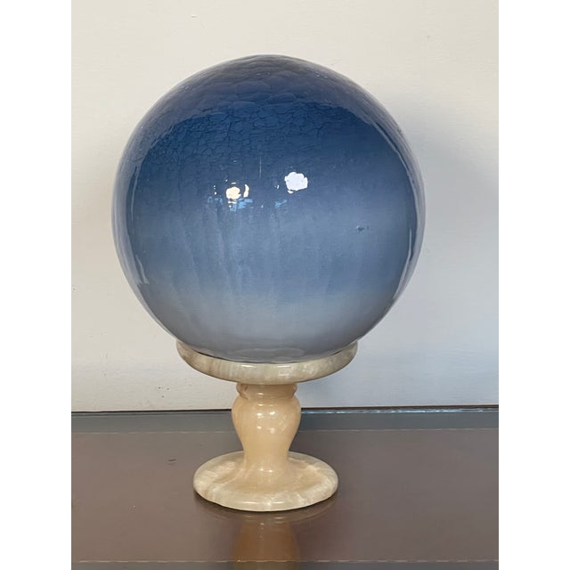 Art Glass blown crackled globe in shades of blue , 8”, on an onyx stone stand.