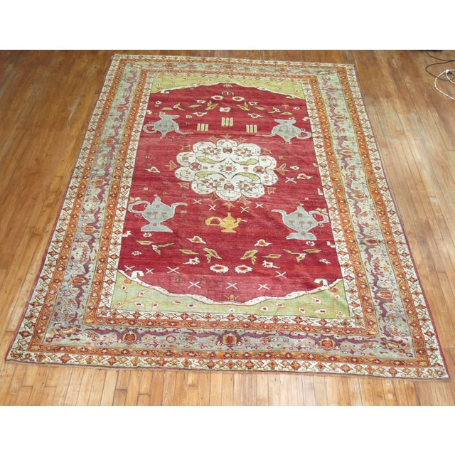 An early 20th century Turkish Oushak rug. 4 teapots on a rich cherry color field, accents in lime green, gray , and orange...