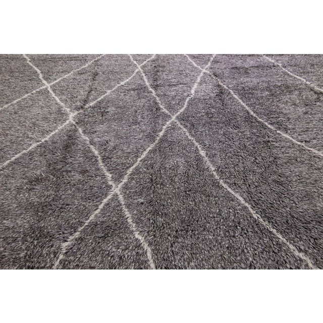 This crafted Moroccan-inspired rug features a captivating tribal design in a gray field that has been meticulously hand-...