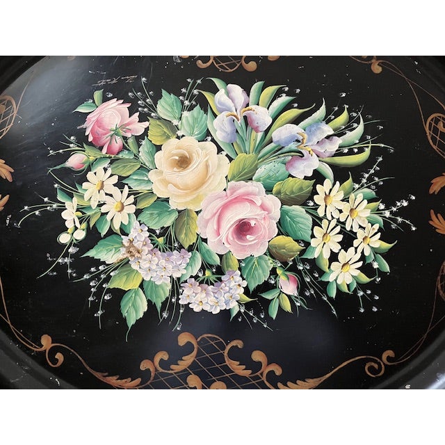 Mid 20th century large oval tole tray is hand painted and signed by the artist. The background of the tray is black with...