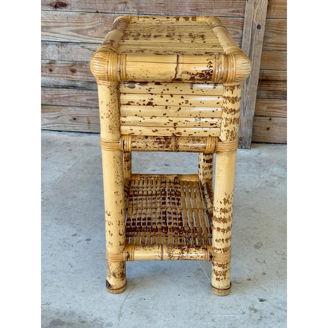 A charming vintage bamboo side table showcasing a rich tortoise finish in a Coastal Organic Modern style. Thoughtfully...