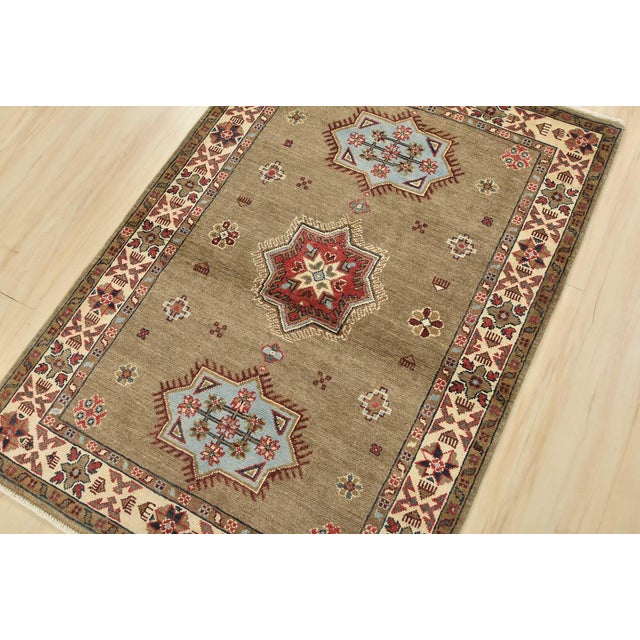 A tribal Caucasian Kazak rug hand-knotted with an all-wool pile on a cotton foundation. This oriental rug features...