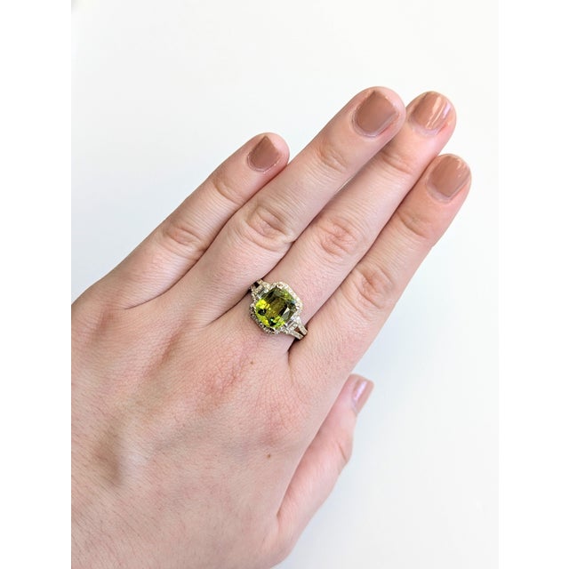 A rare sphene shines in a fiery green-gold at the centre of this solid 14K yellow gold ring, encircled by sixty earth-...