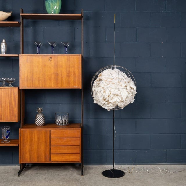 A sculptural floor lamp constructed around a circular metal wire sphere containing crumpled white paper elements,...