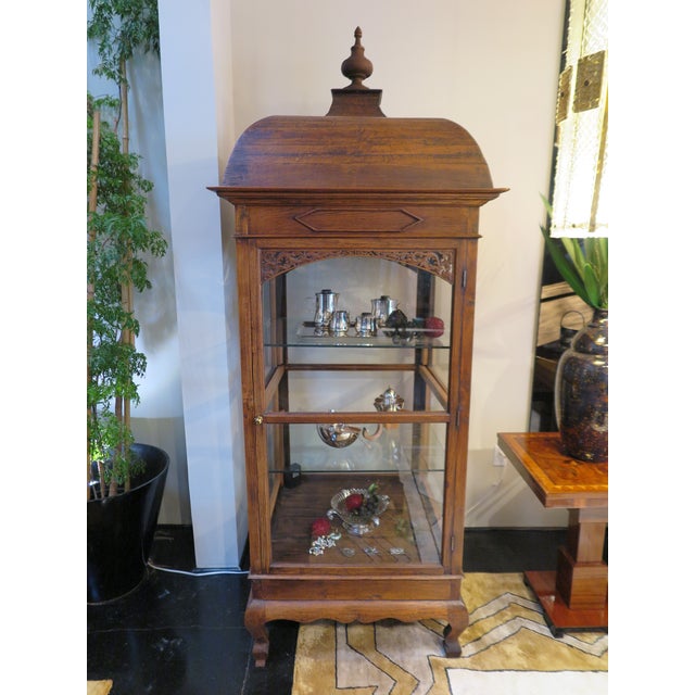 Early 20th century wooden vitrine from Eastern Europe. All four walls in glass with two shelves inside. Floral relief...