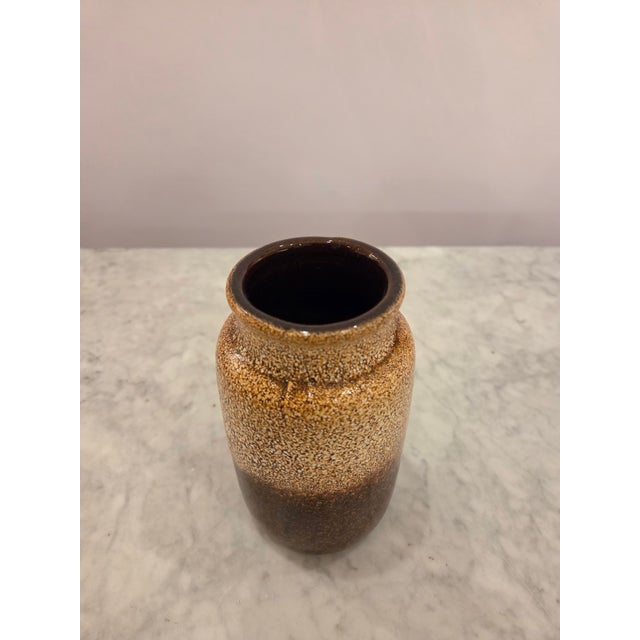 A charming vintage ceramic vase featuring a rich brown drip glaze finish with warm speckled caramel and amber tones. The...
