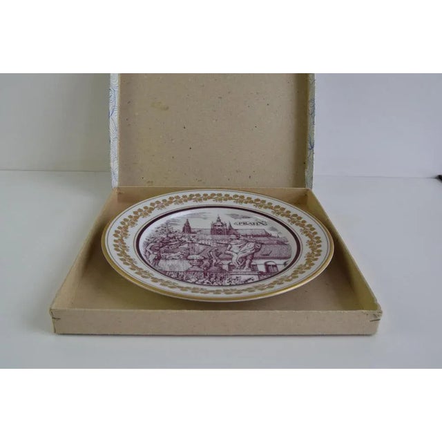 A beatiful vintage porcelain plate by Epiag Orion, featuring a detailed depiction od Prague. The central image shows...
