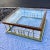 Large brass plated aluminum fireplace fender style plinth base under heavy beveled edge glass inset top, having hardwood...