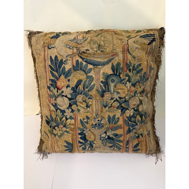 A striking decorative pillow featuring an antique early 18th-century needlepoint face, finished with a luxurious velvet...