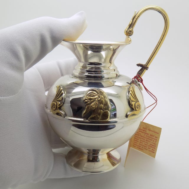 This Italian silver decorative vase incorporates mixed stylistic elements from ancient Near Eastern art, referencing...