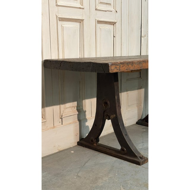 Rustic industrial chestnut wood table, crafted from a single thick plank and supported by sturdy cast iron legs. A piece...