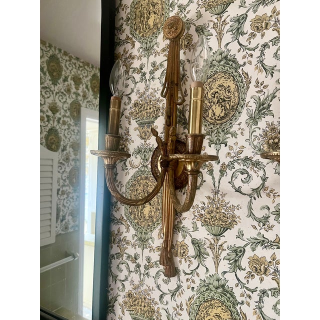 Gorgeous pair of French gilt bronze or brass double-arm wall sconces. These vintage Louis XVI style sconces feature a...