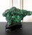 A natural malachite rock specimen with striking green and black colors fitted on a wood stand for viewing and meditating....