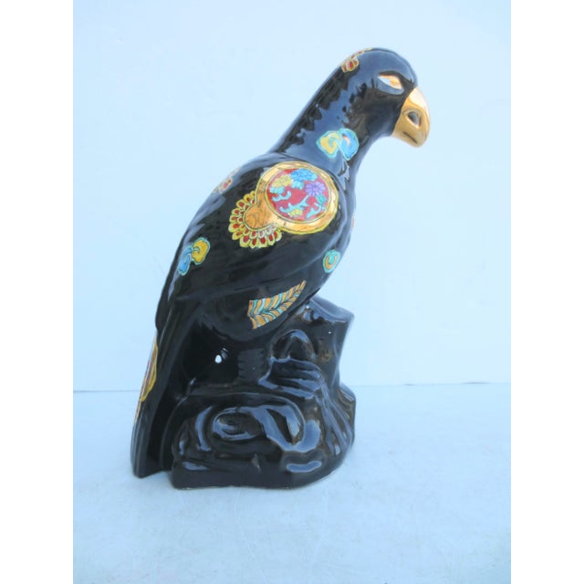 Shiny Black parrot on a rock with gold medallions and ornamental Tao signs over the body. Glossy black and bright mirror...