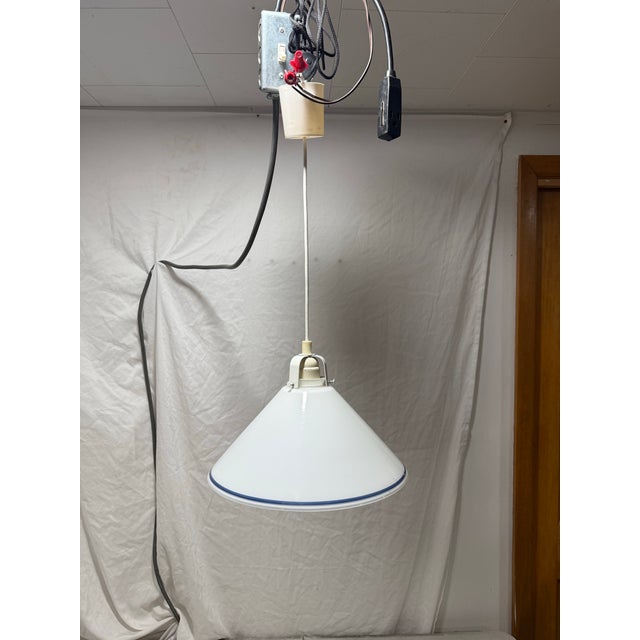 A vintage pendant light fixture featuring a cone-shaped shade made of white milk glass with a blue ring accent. Perfect...