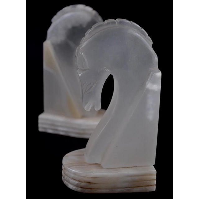 A sculptural pair of translucent alabaster horse head bookends, defined by soft glow and natural stone variation. Elegant...