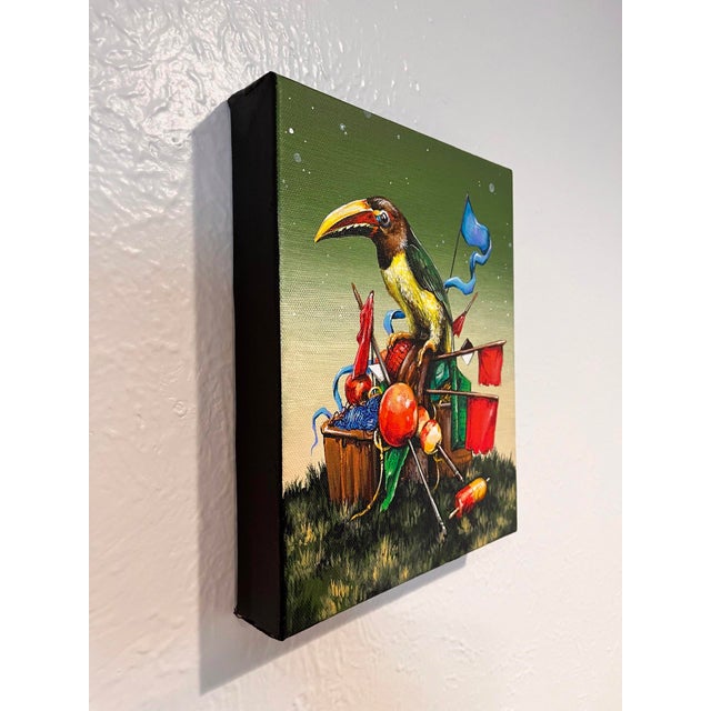 This artwork depicts a vibrant bird perched atop a whimsical arrangement of assorted objects, including colorful flags and...