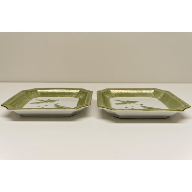 Elegant pair of Asian-inspired square porcelain plates featuring a beautifully detailed pheasant motif, framed by a sage...