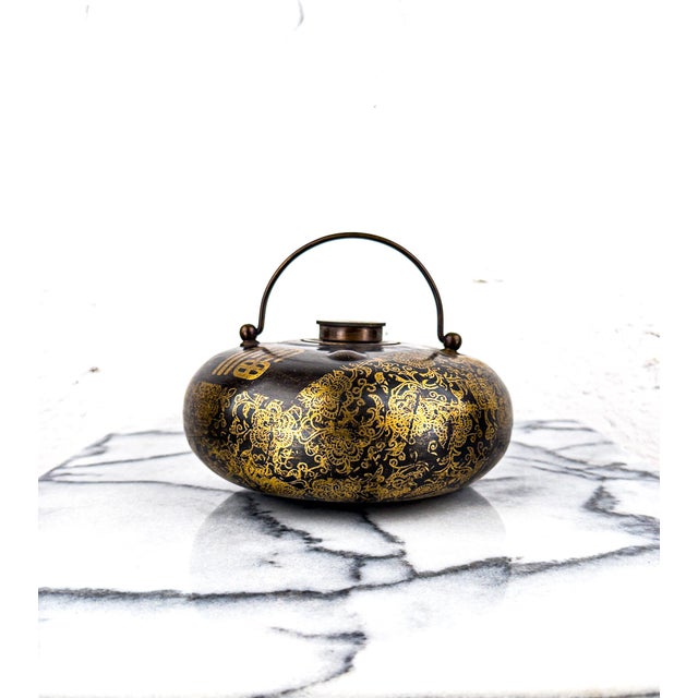 An intricately decorated brass water container, used as a bed warmer, from early 20th century China. The screw-in lid...