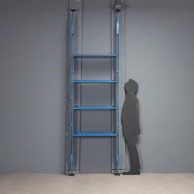 Bookcase in the style of Franco Albini, with ceiling anchoring, adjustable open shelves, lacquered wood. This piece is...