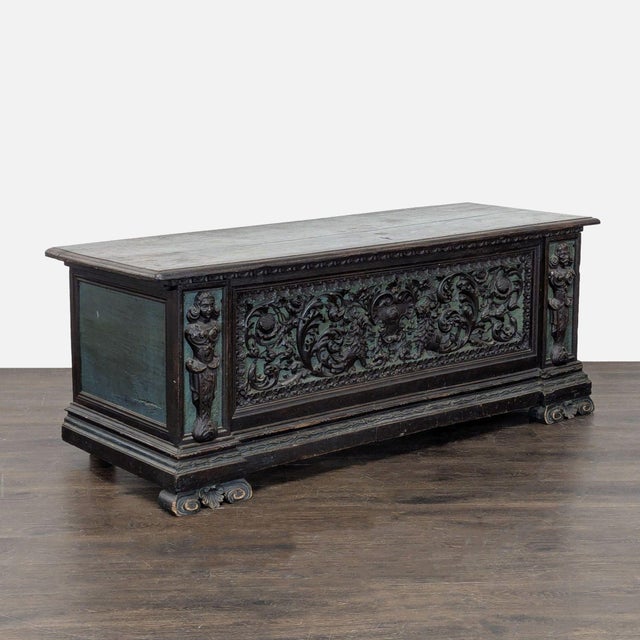 Intricate carving on body with figurative depictions at corners. Original metal hardware hinging. Dimensions (in): 68W x...