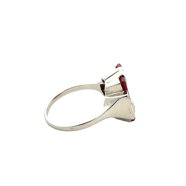 This vintage ring is crafted in solid 14K white gold and features a bold square-cut carnelian center stone with a rich,...
