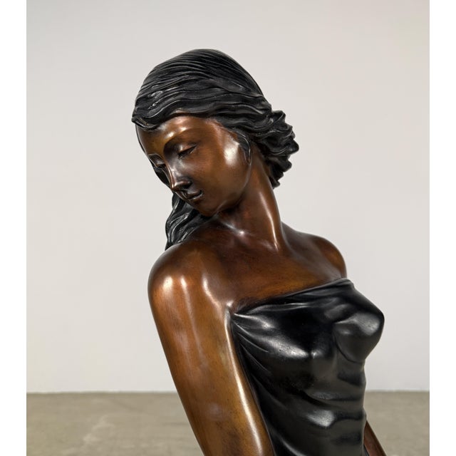 Beautifully executed large-scale bronze sculpture depicting a seated female figure in a graceful pose, holding a bouquet...
