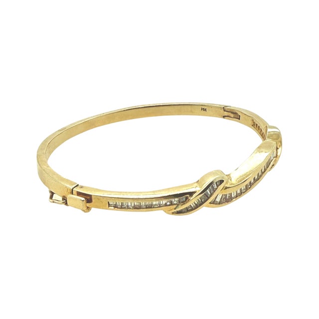 A sculptural gold bangle from around 1980, this 14K yellow gold bracelet carries channel-set baguette diamonds in a...