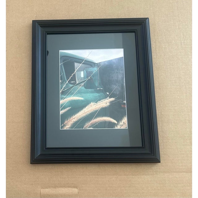 This atmospheric fine art photograph features a vintage truck partially obscured by wild grasses, creating a nostalgic and...