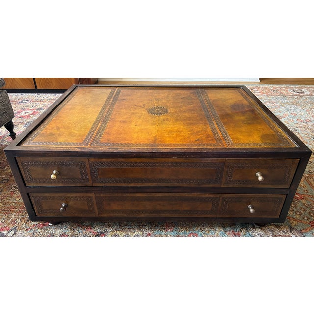 This is a wooden with tooled leather low chest with two drawers that is used as a coffee table. It is a vintage item with...