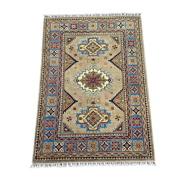 This naturally dyed wool rug features three bold Kazak medallions on a warm beige field. A sky blue border frames the...