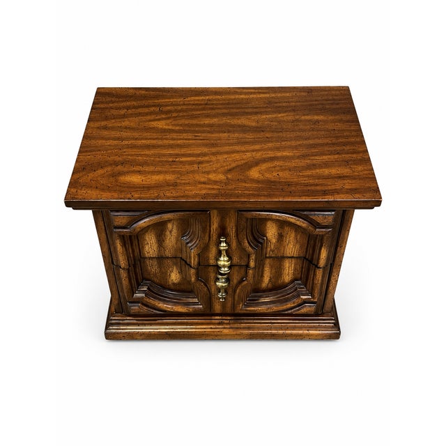A distinctive vintage two-drawer nightstand or end table dating approximately to the 1970s. The piece features a richly...