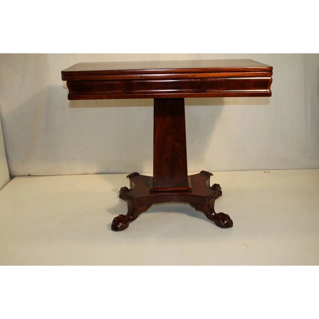 Antique Empire Game card table from the 19th century made of solid mahogany featuring a rectangular flip top above a...