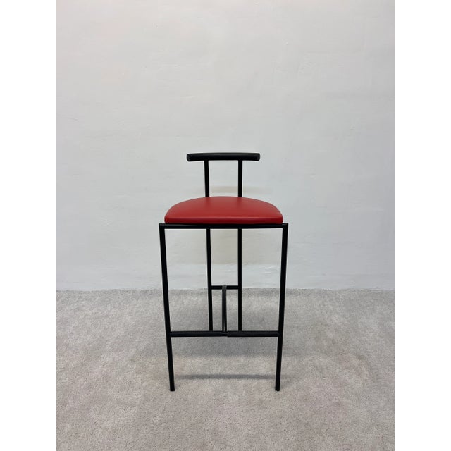 Postmodern Tokyo counter stool made of a satin black steel frame, curved black polyurethane backrest and a red naugahyde...