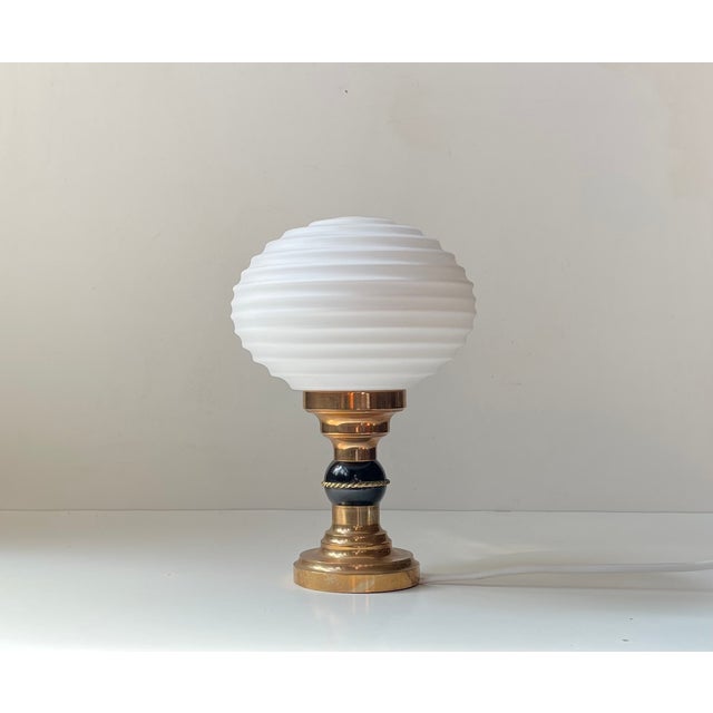 A stylish art deco revival table light. It features a stepped bronze base, black orb center sphere and a horizontally...
